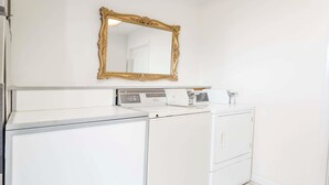A laundry area with a white washing machine, dryer, and a gold-framed mirror on the wall. - Days Inn by Wyndham Kimball (Kimball)