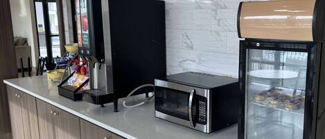 Eine Küchenzeile mit Kaffeemaschine, Mikrowelle und Broitauslage.