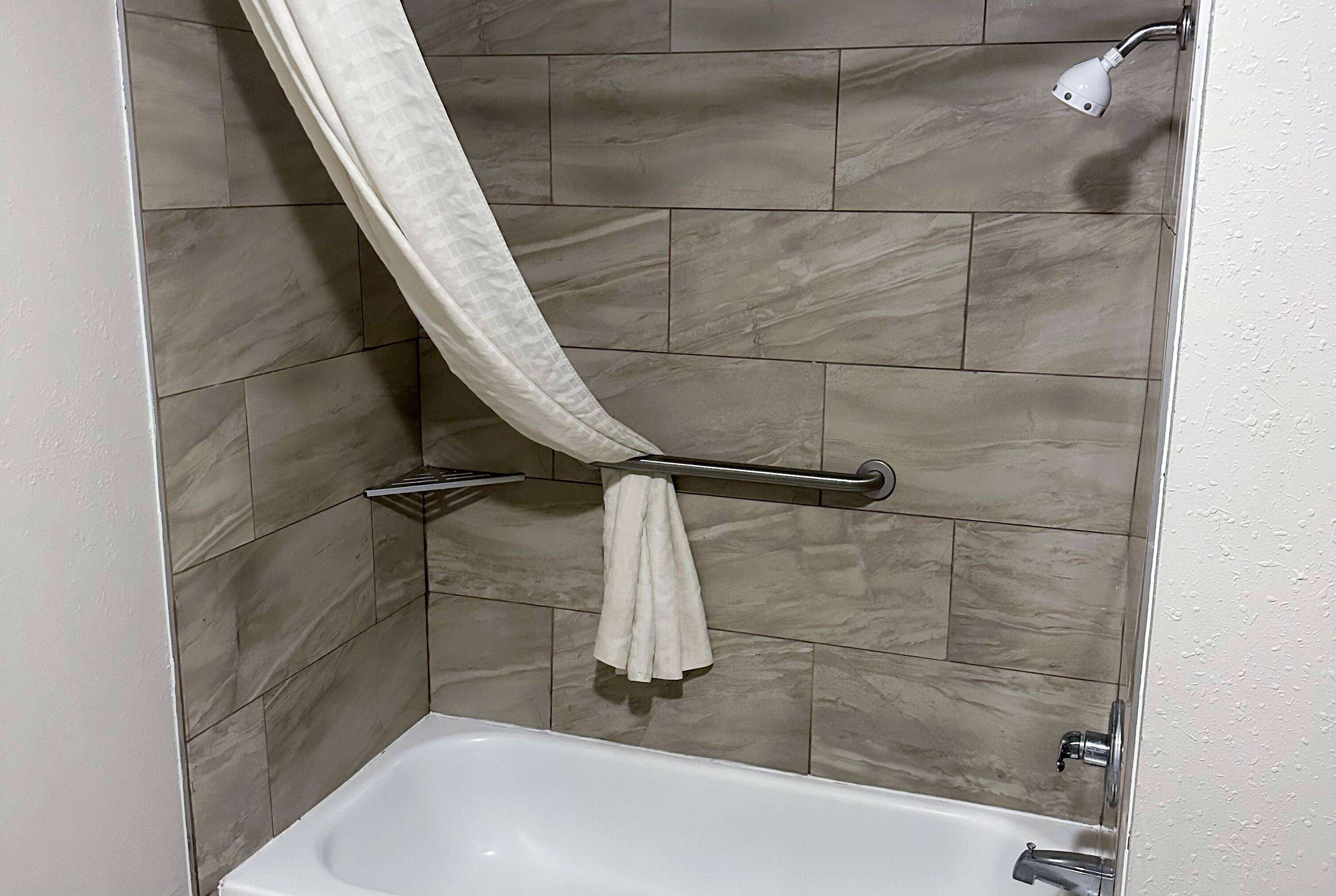 A bathroom with a bathtub, a towel rack, and a showerhead.