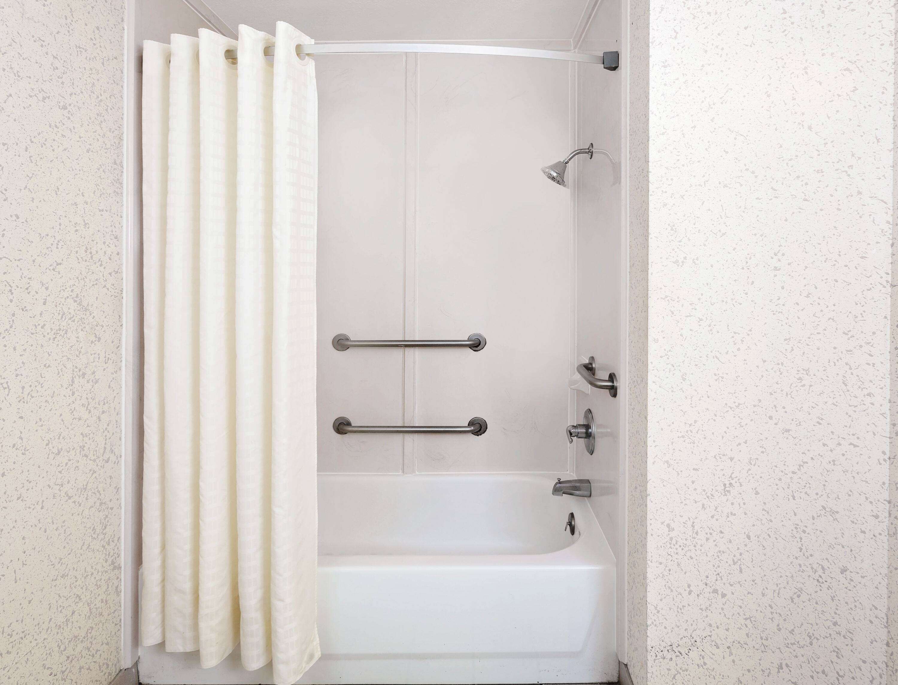 Une salle de bain équipée d’une baignoire, d’une douche et de deux porte-serviettes.
