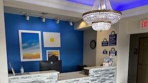 A reception desk with a stone facade, blue walls, and a chandelier. - Days Inn & Suites by Wyndham Opelousas (Opelousas)