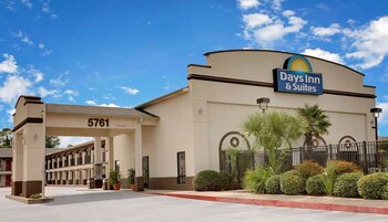 Edificio de Days Inn & Suites con entrada despejada, número 5761, y un área de estacionamiento con bordillo rojo.