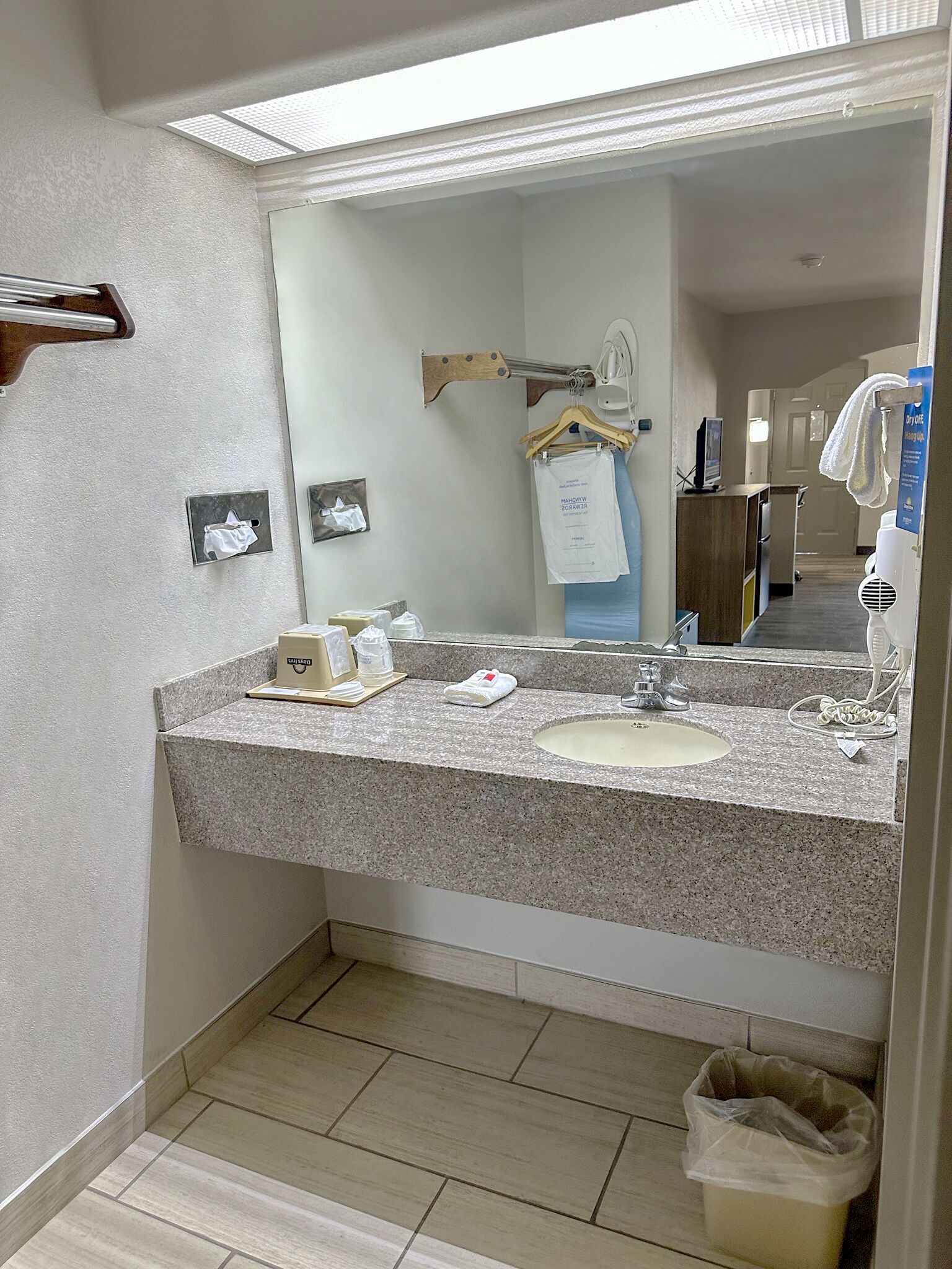 A bathroom with a granite countertop, a sink, a mirror, and a towel rack.