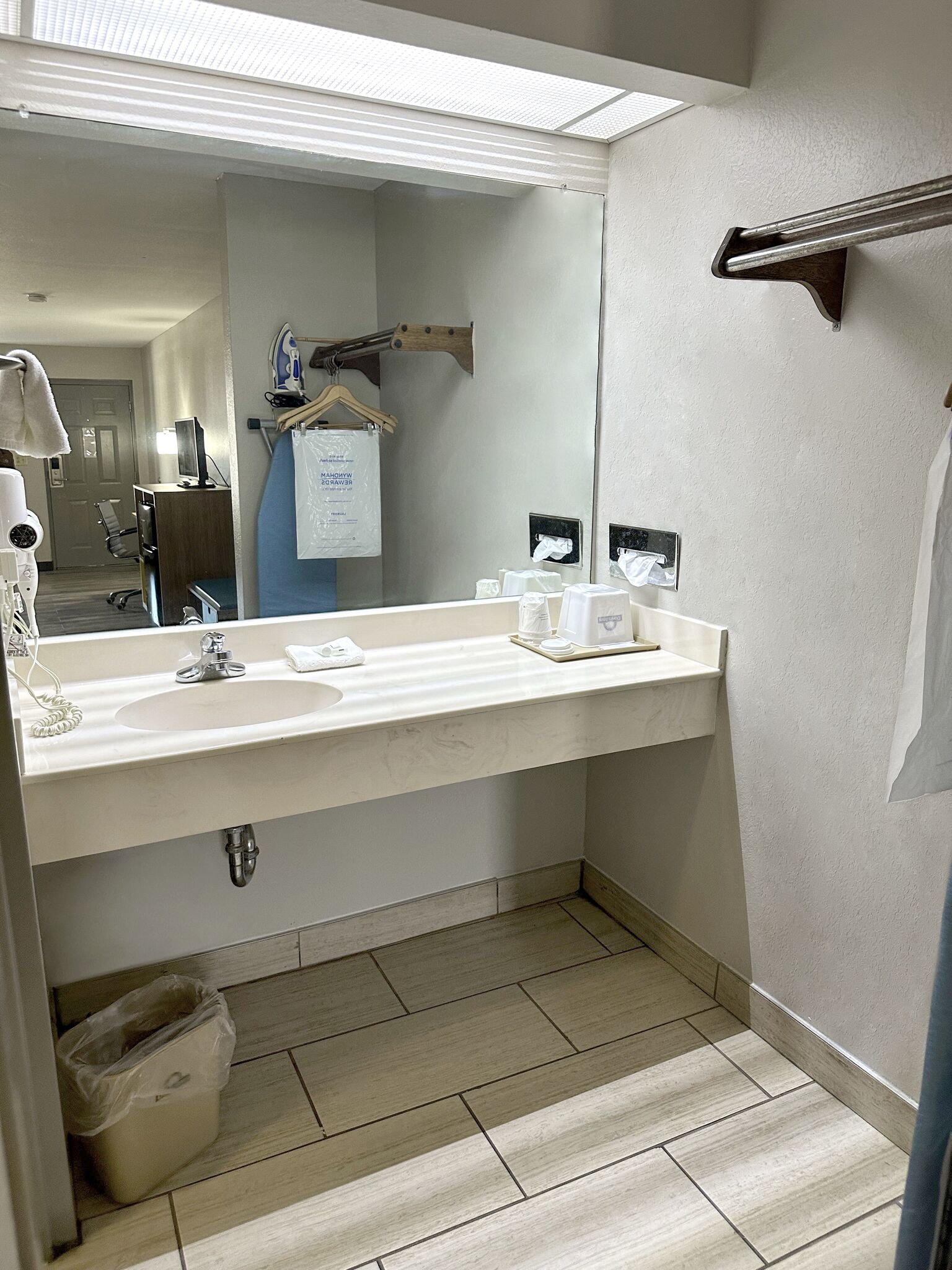 A hotel bathroom with a large mirror, a sink, and a shower area.