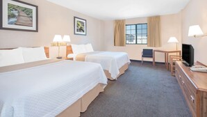 A hotel room with two beds, a desk, a chair, a TV, and two lamps.