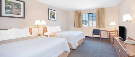 A hotel room with two beds, a desk, a chair, a TV, and two lamps.