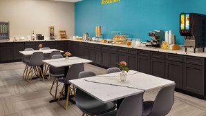 Un espace dédié au petit-déjeuner, comprenant un comptoir, des machines à café et des sièges.
