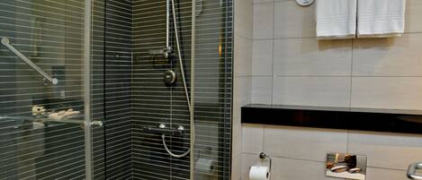 Un baño moderno con cabina de ducha de vidrio, dispensador de papel higiénico y toallero.