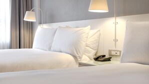 A hotel room with two beds, a bedside table with a phone, and two wall-mounted lamps. - ANEW Hotel Roodepoort Johannesburg (Roodepoort)