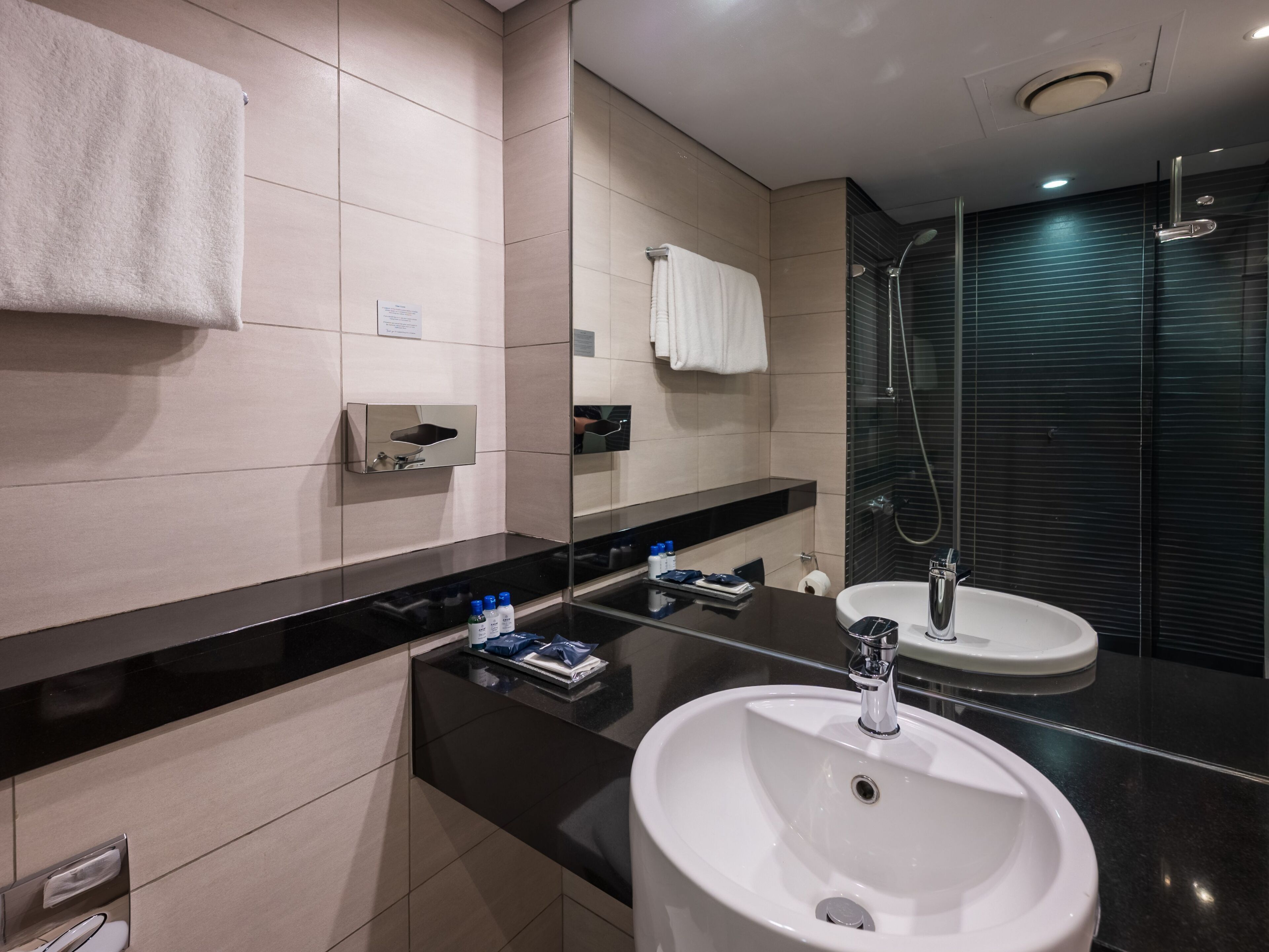 Un ba ño moderno con dos lavamanos, un espejo, un perchero para toallas y una ducha.
