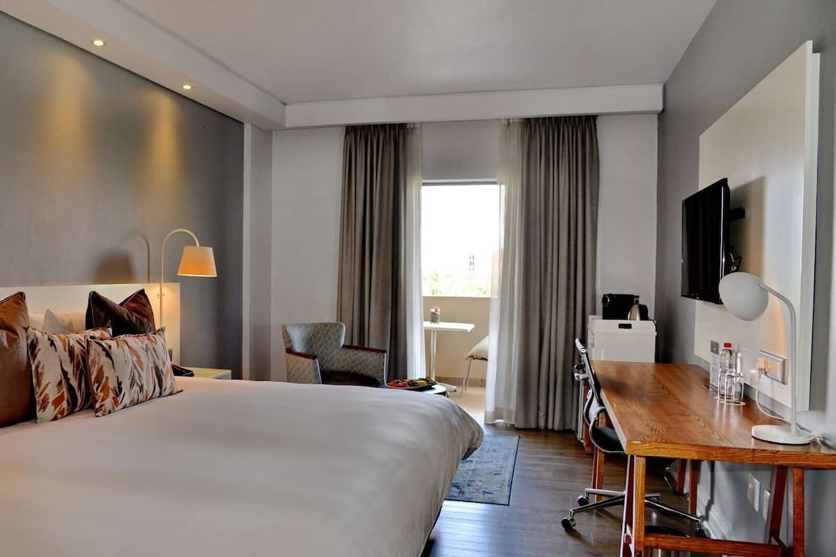 Une chambre d’hôtel moderne équipée d’un grand lit, d’un bureau, d’une chaise et d’un téléviseur.