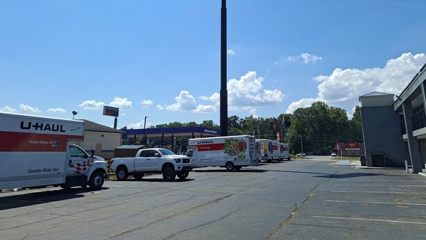 Un camion U-Haul est garé sur un parking, avec une enseigne indiquant la présence d’un hôtel du Sud en arrière-plan.