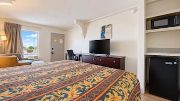 Een hotelkamer met een groot bed, een bureau, een televisie, een magnetron en een koelkast.