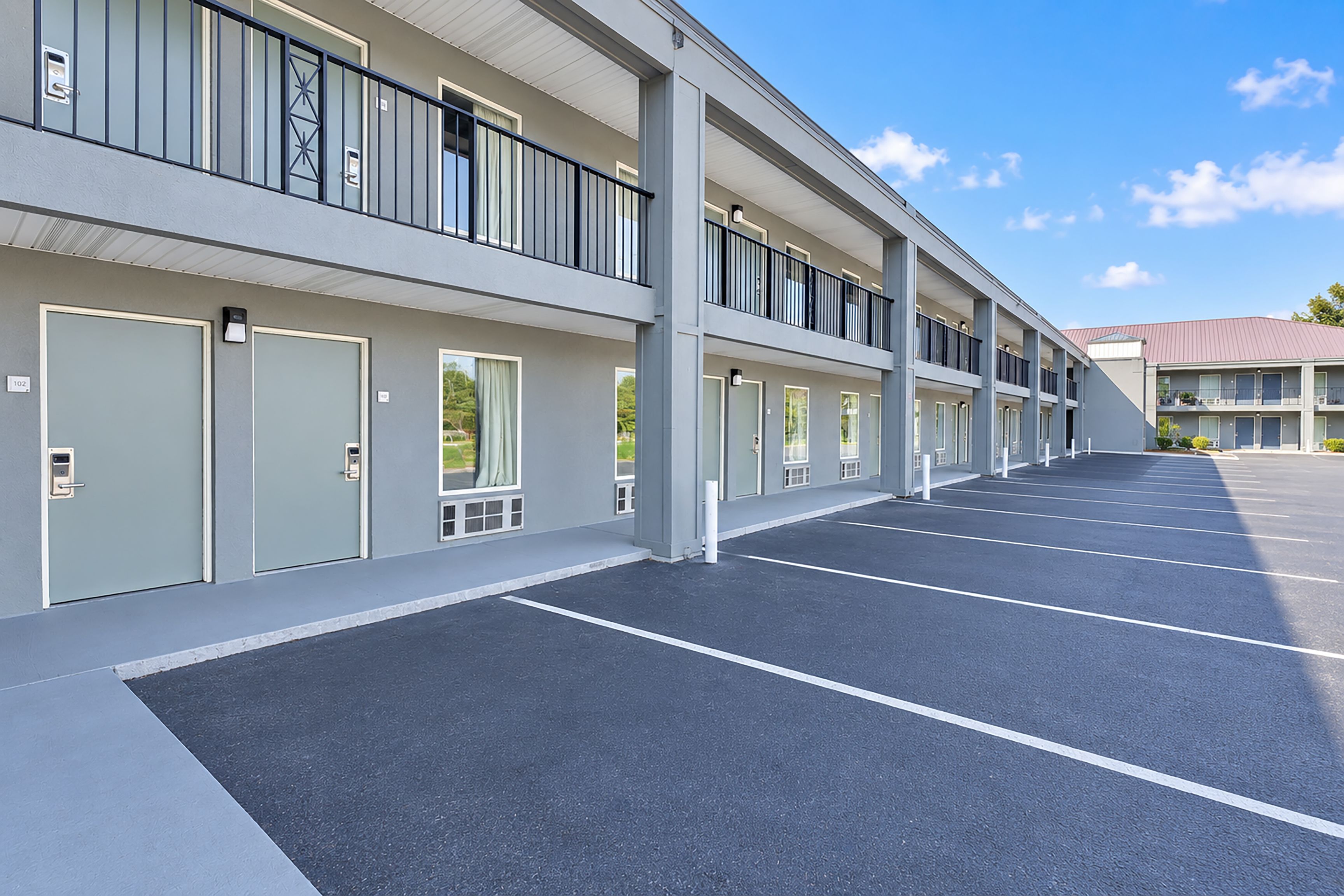 A multi-story parking garage with a row of doors on the ground floor, likely leading to hotel rooms.