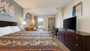 Habitación de hotel con una cama grande, un escritorio, un televisor y vistas al exterior.