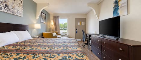 Habitación de hotel con una cama grande, un escritorio, un televisor y vistas al exterior.