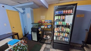Une pièce équipée d’un distributeur automatique de boissons, d’un petit réfrigérateur et d’un bureau avec une chaise.