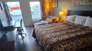 Une chambre d’hôtel avec un grand lit, un bureau, une chaise et une vue sur l’extérieur.