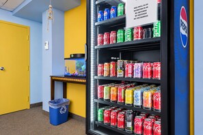 A vending machine stocked with various beverages, a trash bin, and a small table with a fish tank. - Southern Inn Manchester TN I 24 (Manchester)