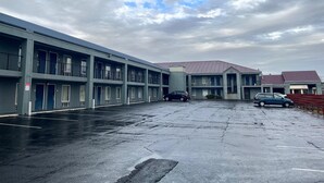 A multi-story motel with a parking lot, featuring a central building with a red roof and several smaller units on either side. - Southern Inn (Manchester)