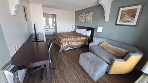 Une chambre d’hôtel avec un lit, un bureau, une chaise, un canapé et un tableau au mur.