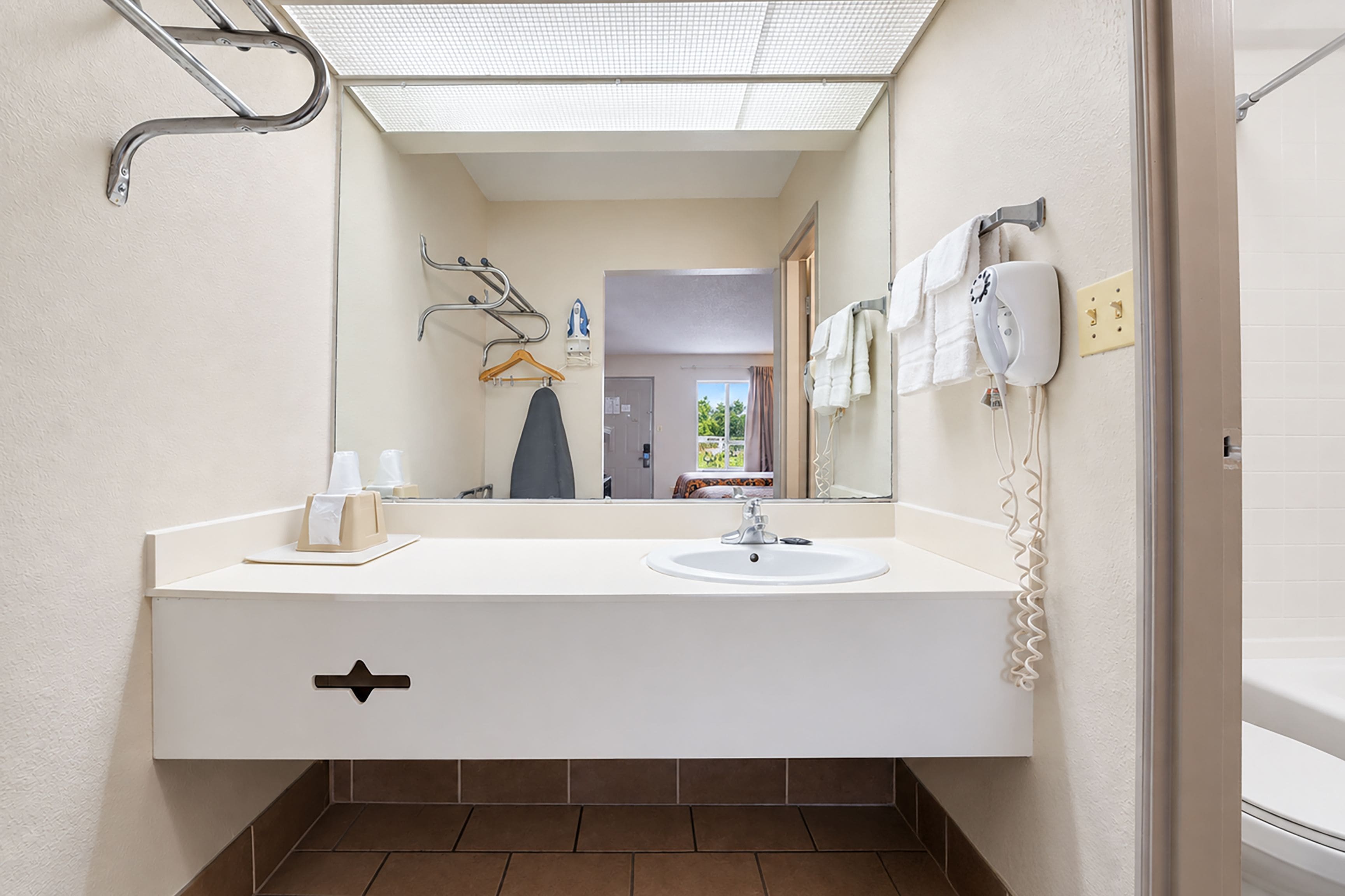 A bathroom with a white sink, a mirror, a towel rack, and a hairdryer.