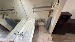 A bathroom with a double sink, a mirror, a towel rack, a shower area, and a microwave. - Southern Inn (Manchester)