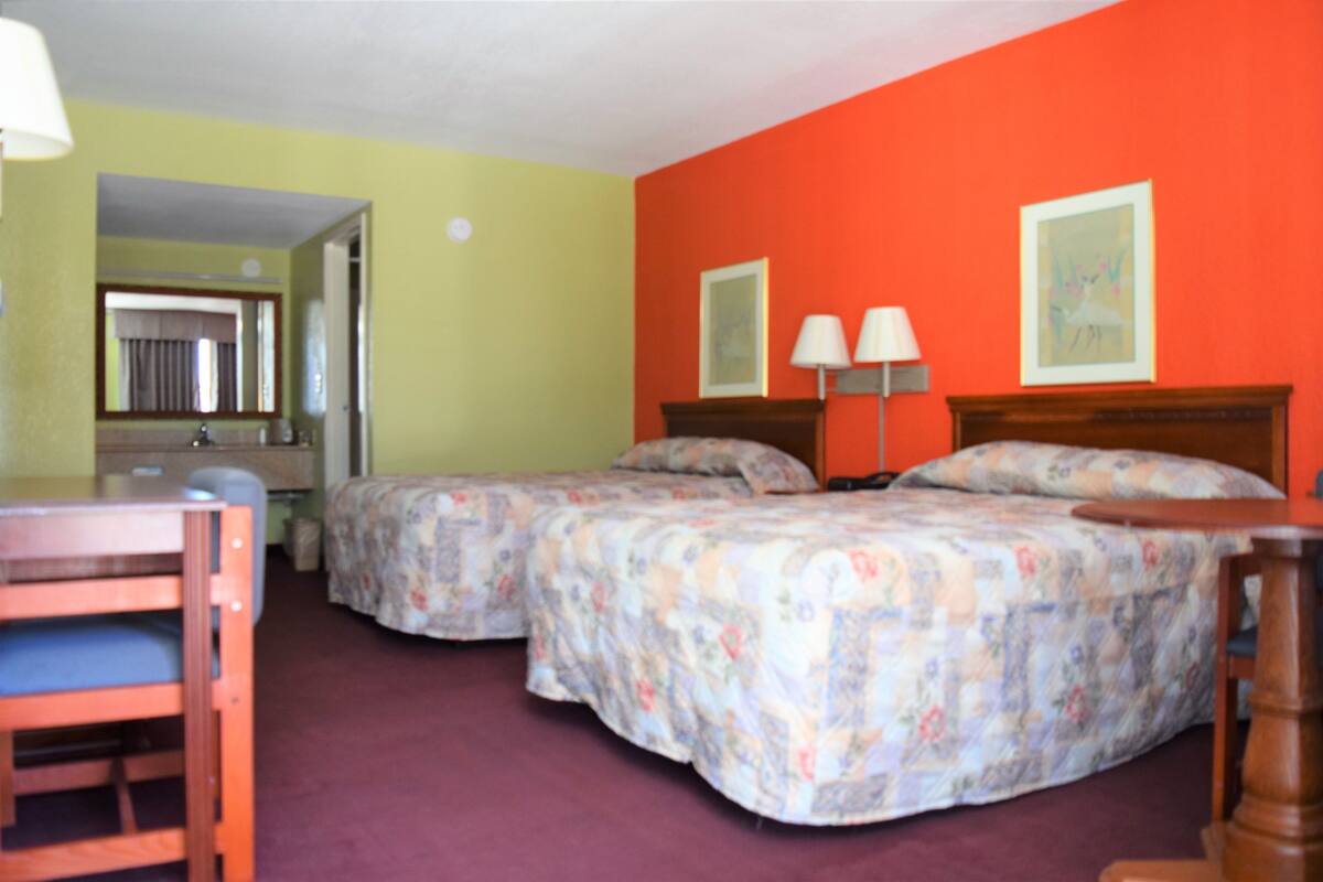 A room with two beds, a desk, and a chair.