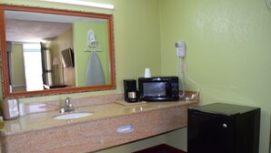 A bathroom with a sink, mirror, microwave, and hairdryer. - Liberty Inn (Waynesboro)