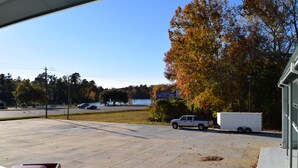 A parking lot with a white truck and a trailer, trees with autumn foliage, and a clear blue sky. - Liberty Inn (Waynesboro)