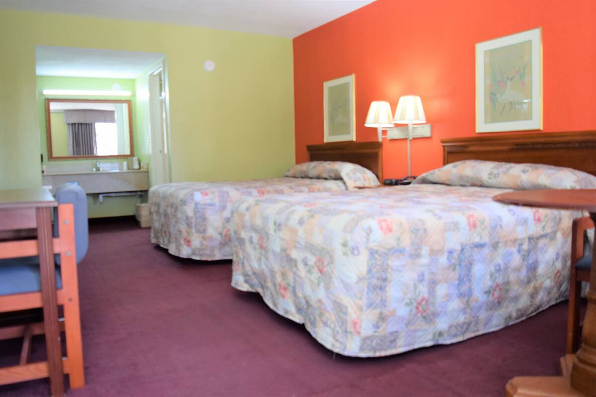 A hotel room with two beds, a desk, and a chair.