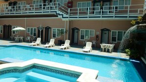 A hotel with a swimming pool, lounge chairs, and a water feature. - Hotel Villa Fontana Inn (Ensenada)