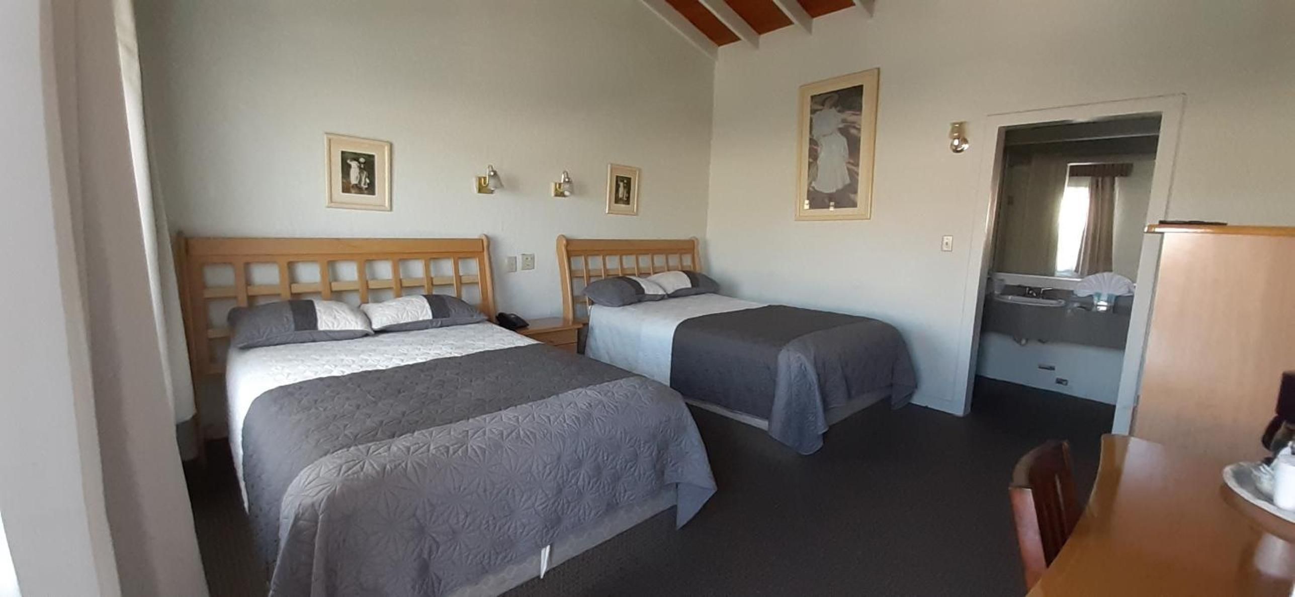 A room with two beds, a small table, and a mirror.