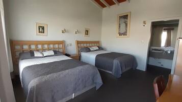 A room with two beds, a small table, and a mirror.