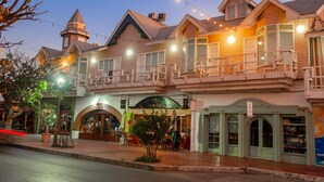 A traditional wooden building with a balcony, storefronts, and a street lamp. - Hotel Villa Fontana Inn (Ensenada)