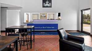 A reception area with a blue banner, a framed picture, and a black chair. - Americas Best Value Inn Gonzales (Gonzales)