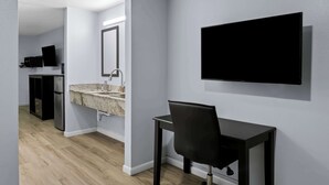 A modern bathroom with a sink, mirror, and black chair. - Americas Best Value Inn Gonzales (Gonzales)