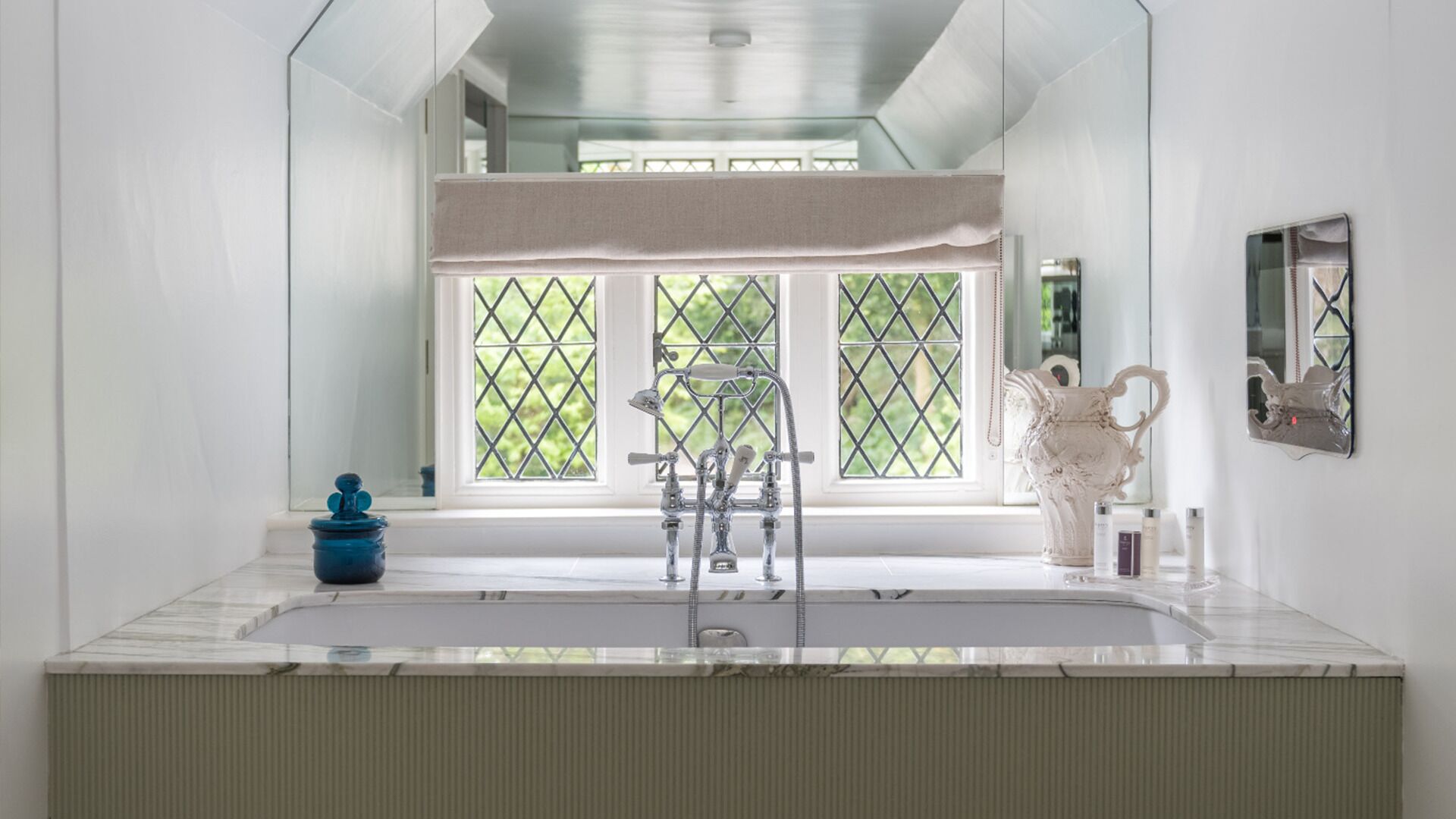 A bathroom with a large window, a bathtub, a shower, and a mirror.