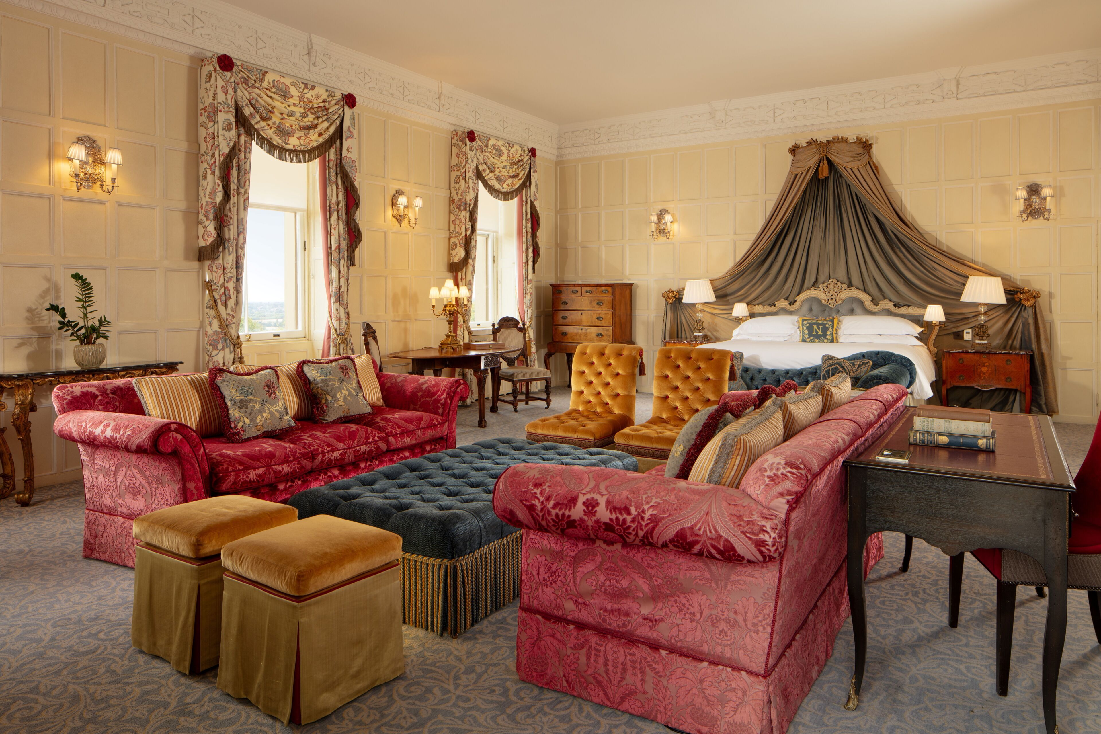 A luxurious bedroom with a large bed, multiple sofas, and a dining area.