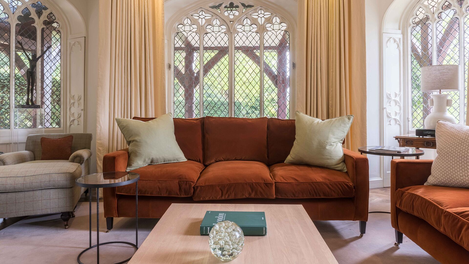 A cozy living room with a brown sofa, two armchairs, a coffee table, and a decorative glass vase.