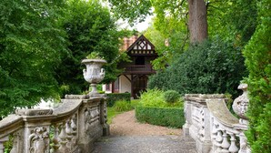 Un vialetto che conduce a un edificio in stile Tudor con un balcone in legno.
