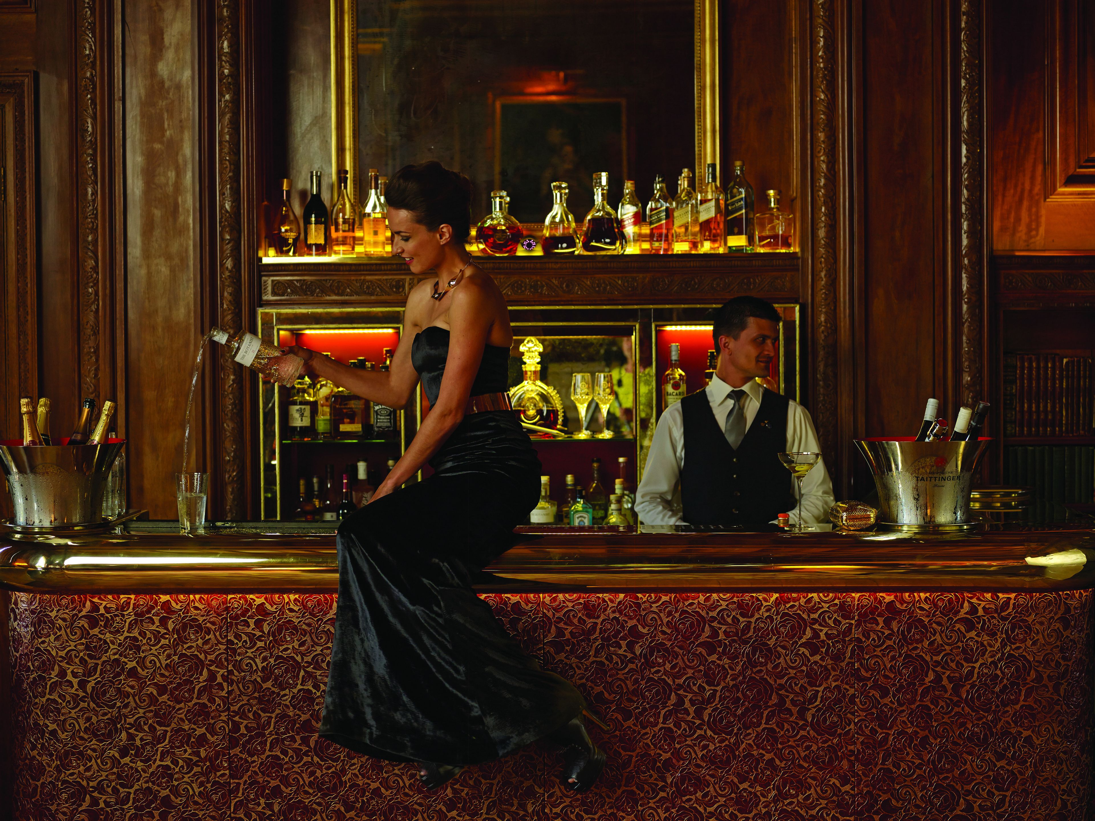 A bar area with a bartender and a woman in a black dress.