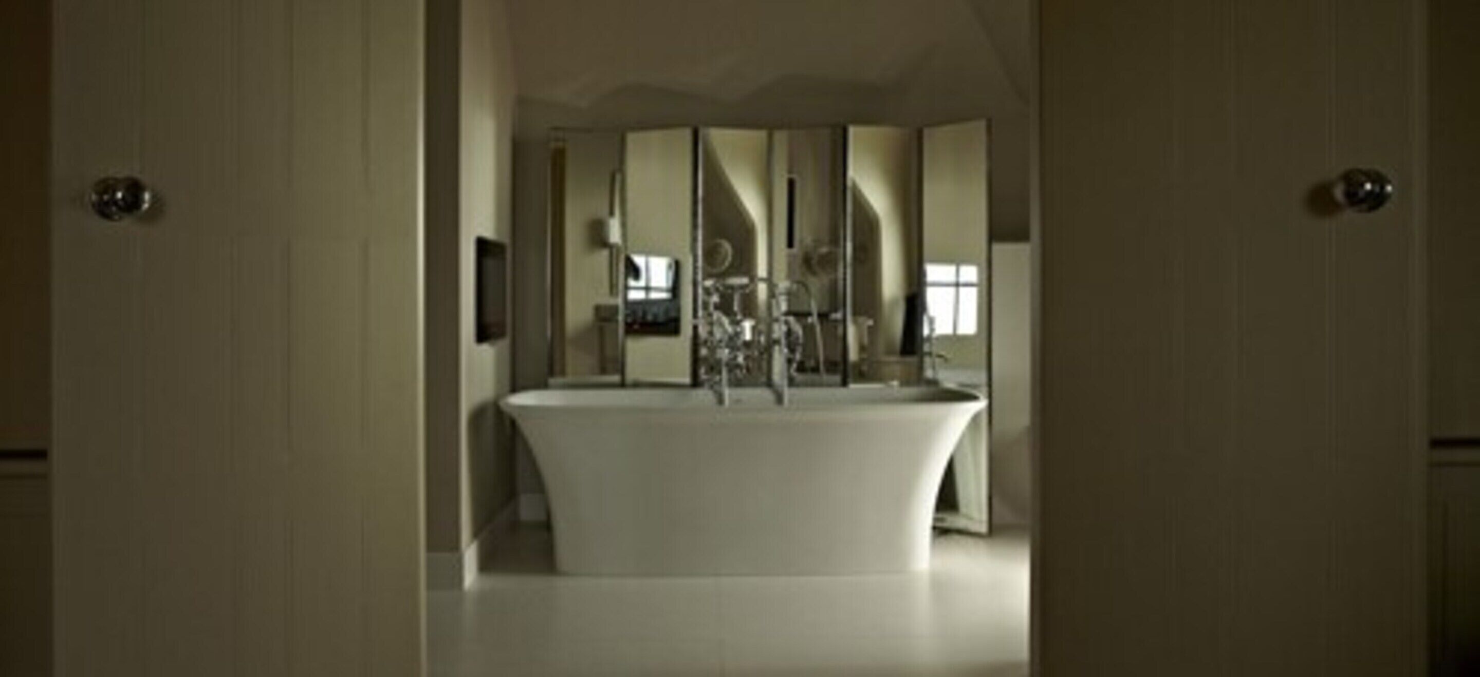 A modern bathroom with a freestanding bathtub, a large mirror, and a vanity with a sink.