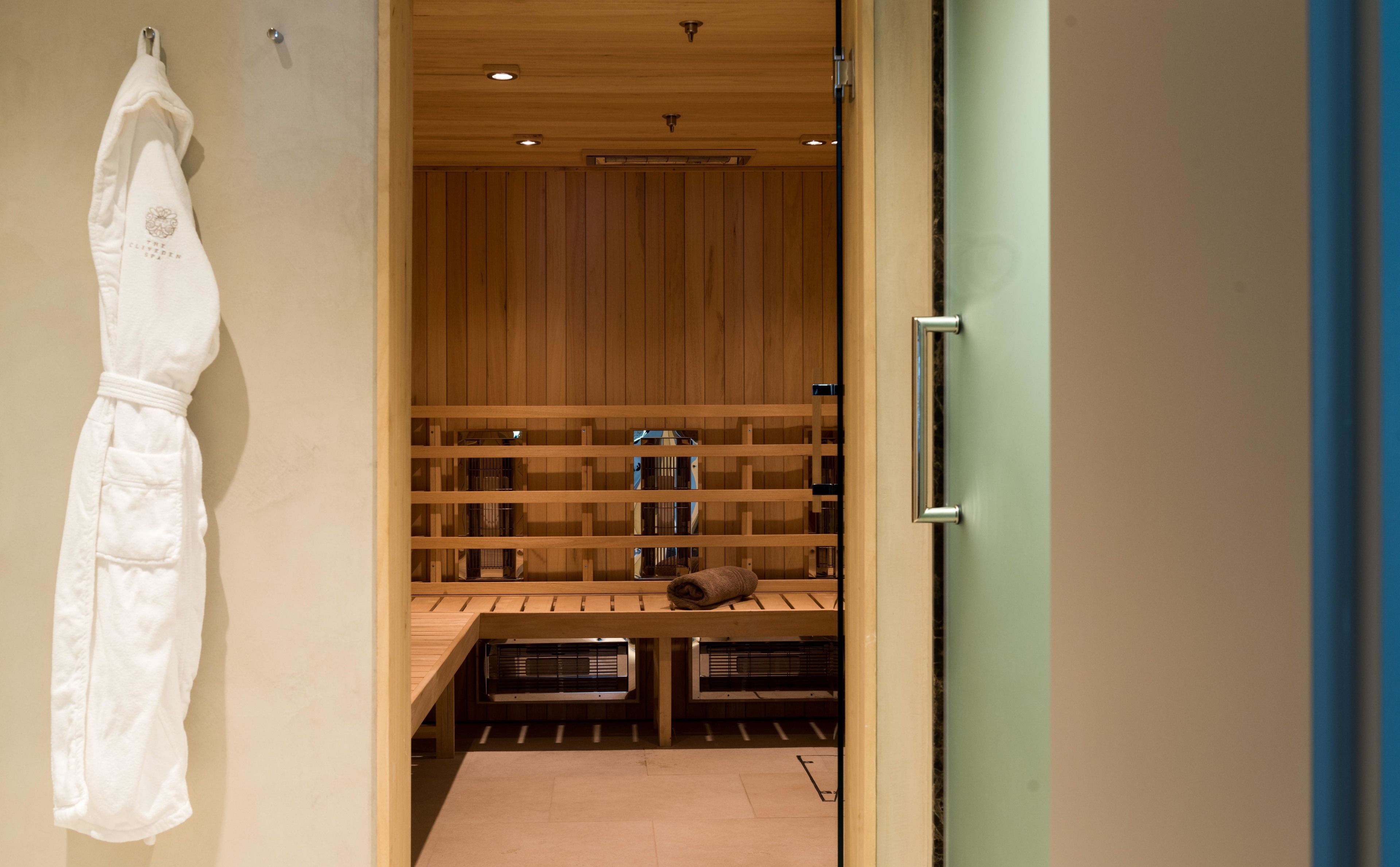 A sauna room with wooden benches and a towel rack.