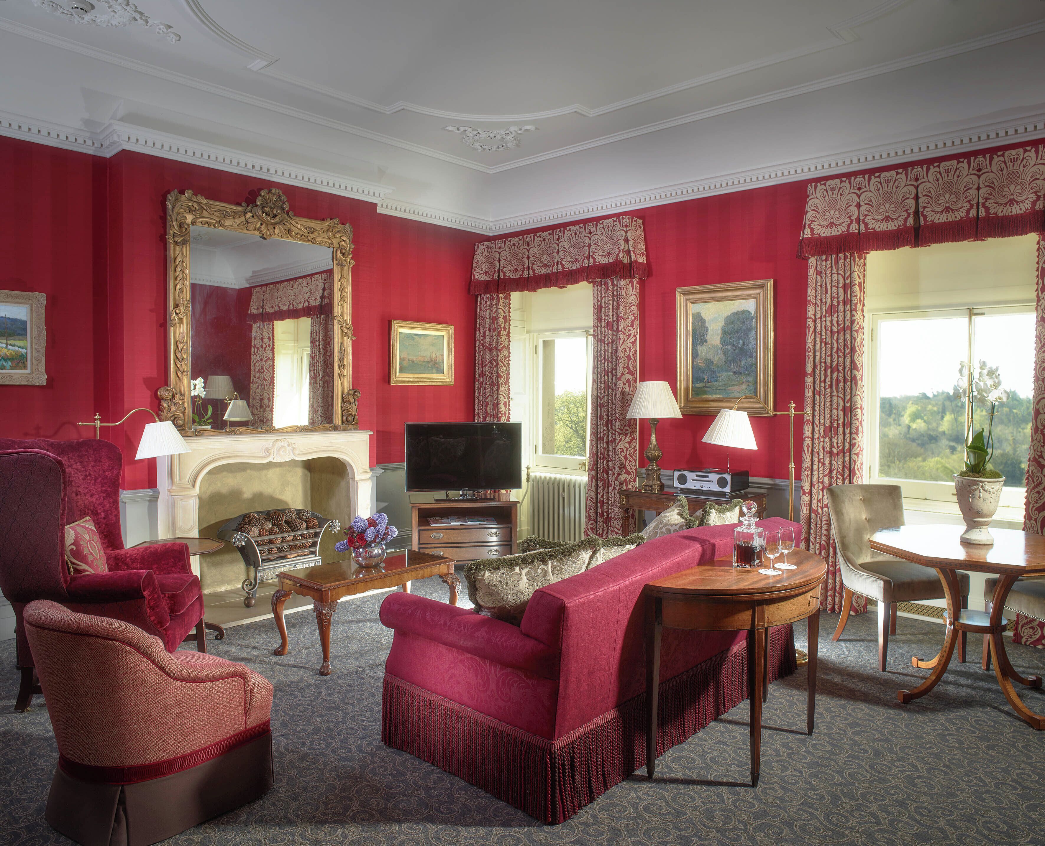 A red-walled room with a fireplace, a television, and a dining table with chairs.
