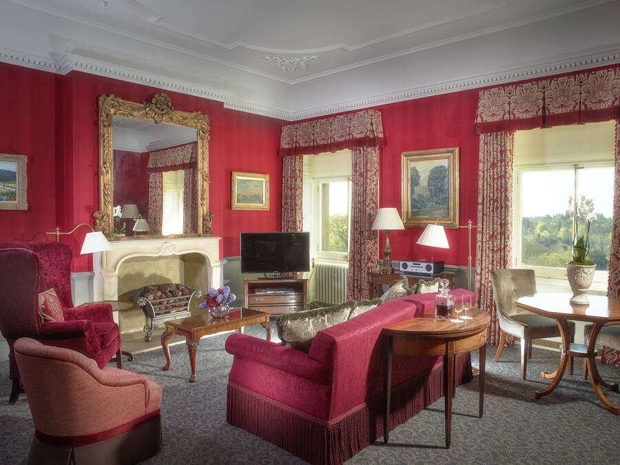 A red-walled room with a fireplace, a television, and a dining table with chairs.