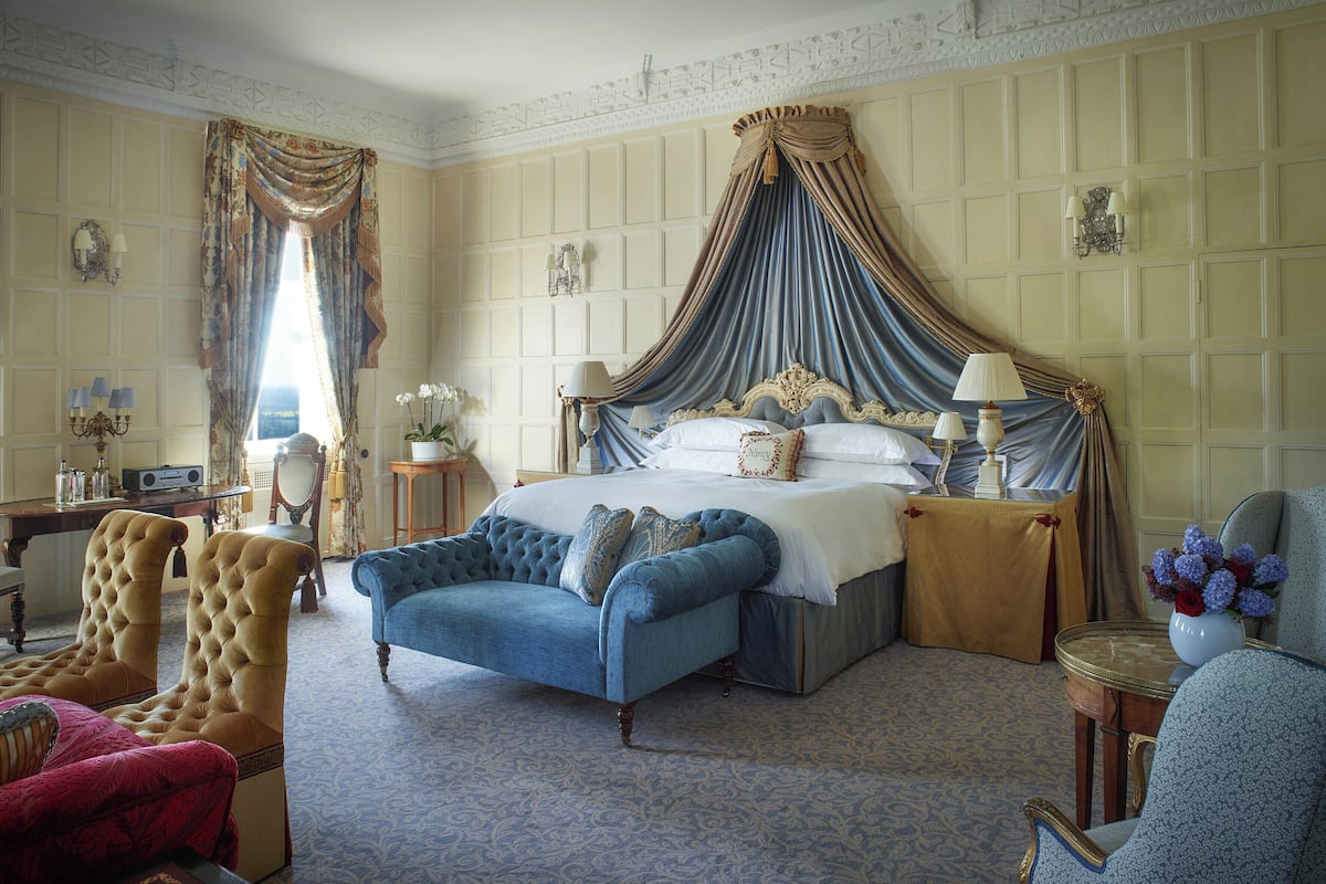 A spacious bedroom with a large bed, a chaise lounge, and a sitting area with a table and chairs.