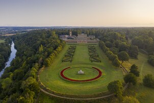 An aerial view of a large estate with a central lawn, a circular garden, and a building with a tower.