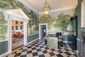 A lobby with a checkered floor, a reception desk, and a mural of trees.