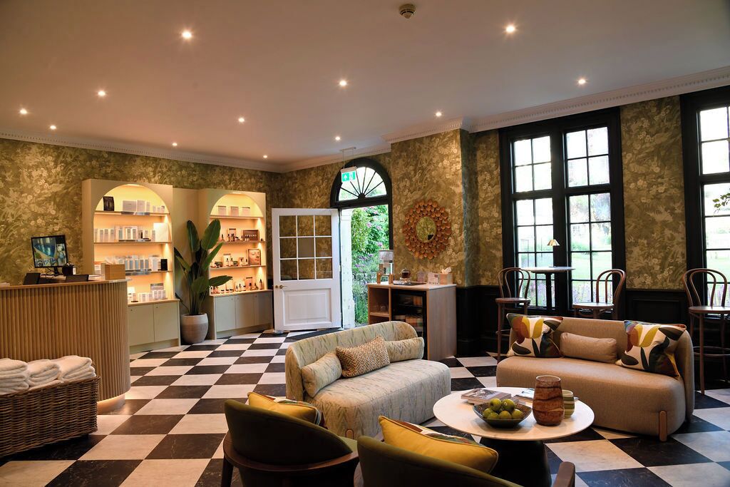 A hotel lobby with a checkered floor, seating area with sofas and chairs, a reception desk, and large windows.